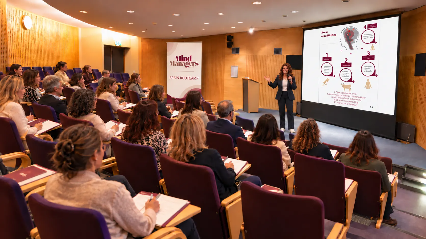 AI-sfeerimpressie: Iris geeft uitleg in het auditorium, met een Brain Bootcamp-sheet op het scherm en fictieve deelnemers in de zaal.